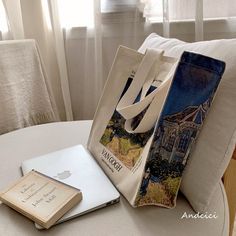 an open book sitting on top of a table next to a bag and laptop computer