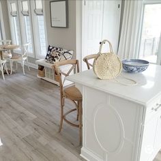 a white kitchen with wooden floors and chairs in front of the counter top, next to a breakfast nook