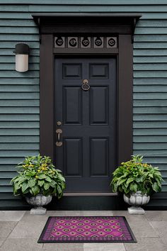 two planters with flowers are next to a door mat on the front step of a house