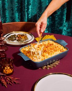 a person is cutting into a casserole dish on a table with other dishes