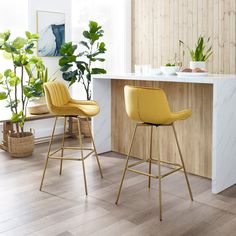 two green bar stools in front of a counter with potted plants on it