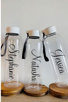 three personalized glass water bottles on wooden coasters