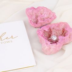 two pink rock like objects sitting on top of a white sheet next to a book