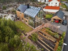 an aerial view of a house with solar panels on the roof and garden beds in front