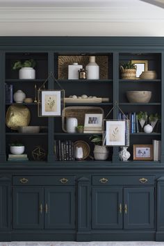 a black bookcase filled with lots of books and vases on top of it