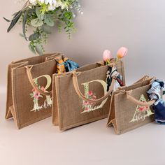 three burlap bags with designs on them sitting next to a bouquet of flowers