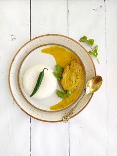 a white plate topped with food next to a spoon