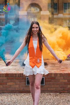 a woman in an orange vest and white dress is holding her arms out as she walks down the street