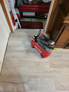 a red lawn mower sitting on top of a wooden floor next to a doorway