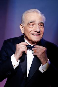 an older man in a tuxedo adjusts his bow tie