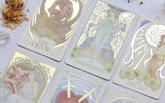 four tarot cards with angels on them sitting next to some dried flowers and herbs