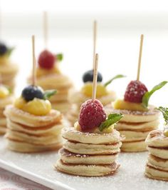 small pancakes with fruit on top and toothpicks sticking out of the stacks are ready to be eaten