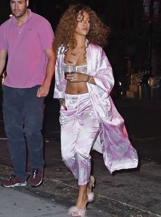 a man and woman walking down the street at night with one wearing a pink shirt