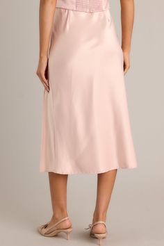 Unleash your inner glam with the Park Avenue Glam Blush Pink Satin Midi Skirt. This statement piece will elevate your wardrobe with its silky, smooth satin fabric and figure-flattering midi length. Perfect for both casual and formal occasions, this skirt will have you feeling confident and stylish all day long. Dress up or dress down, the choice is yours! This blush pink skirt features a high waisted design, an elastic waistband, a slit up the leg, and a satin material.  95% Polyester & 5% Spandex  Unlined  Hand Wash Cold Manufactured in China Designed in The USA  Model is wearing a size small Pink Satin Midi Skirt, Blush Pink Skirt, Sorority Rush Dresses, Rush Dresses, Feeling Confident, Satin Midi Skirt, Dress Bra, Long Crop Top, Park Avenue