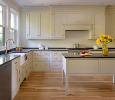 a large kitchen with white cabinets and black counter tops, along with an island in the middle