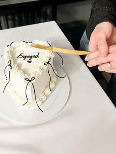 a person is cutting into a heart shaped cake with a knife on the table next to it