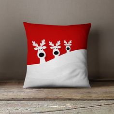 a red and white pillow with two reindeers on it