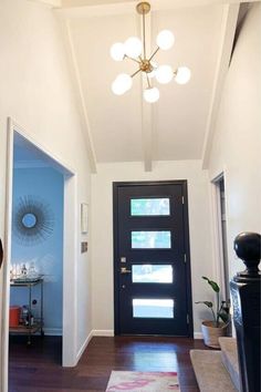 an entry way with a black door and light fixture on the ceiling in front of it