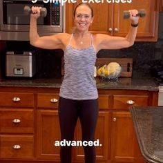 a woman is standing in the kitchen with two dumbs on her shoulders and smiling at the camera