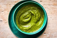 a bowl filled with green sauce on top of a table