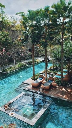 an outdoor swimming pool surrounded by palm trees and lounge chairs in the middle of it