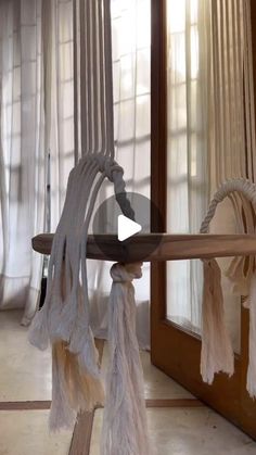 a table with some tassels hanging from it's sides in front of a window