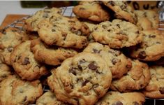 a pile of chocolate chip cookies sitting on top of a cooling rack