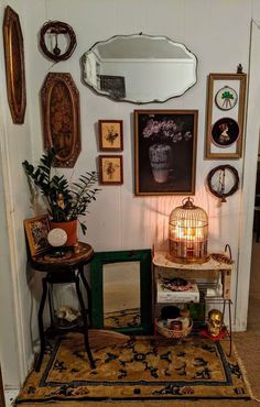 a living room filled with furniture and pictures on the wall next to a table topped with a birdcage