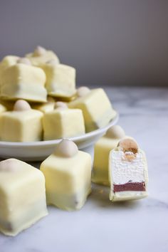 several pieces of white chocolate sitting on a table next to a plate with small marshmallows