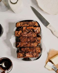 some brownies are stacked on top of each other next to butter and knifes