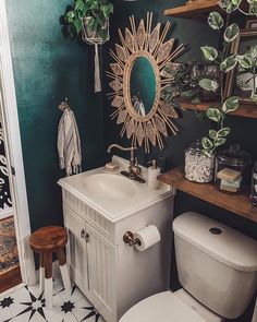 a white toilet sitting next to a sink in a bathroom under a sun shaped mirror