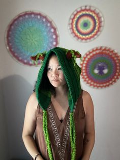 a woman wearing a green hat and scarf in front of art work on the wall