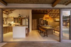 an open kitchen and dining room area with wooden beams on the ceiling is lit by pendant lights