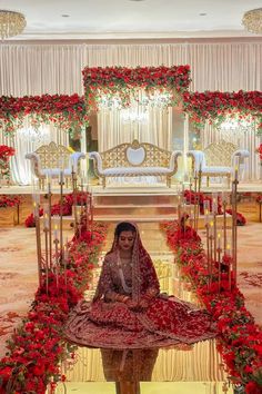 a woman sitting on top of a table in front of red flowers and greenery