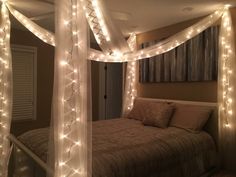 a bed with lights on the headboard and canopy over it in a room that is lit up