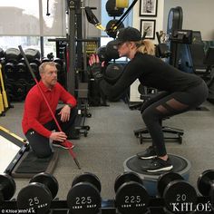 a man and woman squatting down in a gym