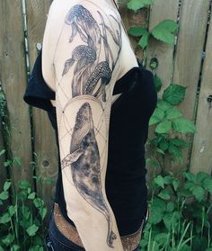 a woman with a tattoo on her back is standing in front of a wooden fence