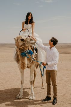 a man standing next to a woman on top of a camel