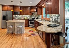 a kitchen with wooden floors and granite counter tops, stainless steel appliances and an island in the middle