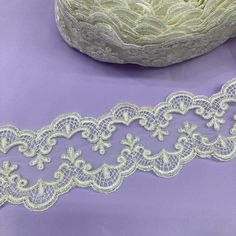 two pieces of white lace sitting on top of a purple surface