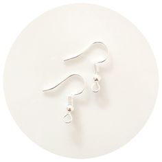 two silver ear hooks on a white circular surface, with one hook in the middle