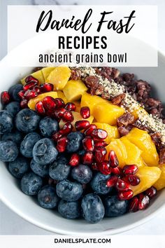 a white bowl filled with blueberries, mangos and other fruits on top of a table