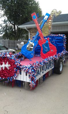 a parade float decorated with red, white and blue decorations in the shape of a guitar