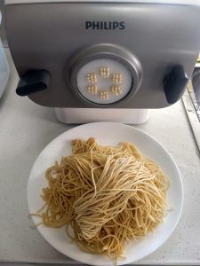 a white plate topped with noodles next to an electric rice cooker