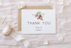 a thank you card with white flowers on it next to a spool of thread