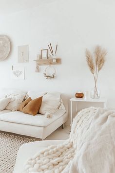 a white couch sitting in a living room on top of a rug next to a table