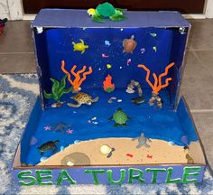 a cardboard box with sea turtle decorations on the inside and under it, sitting on a rug in front of a door