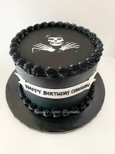 a black cake with white lettering and a skull on the top is sitting on a plate