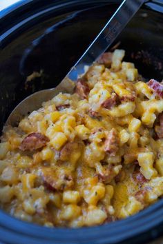 a crock pot full of macaroni and cheese with a spoon in it