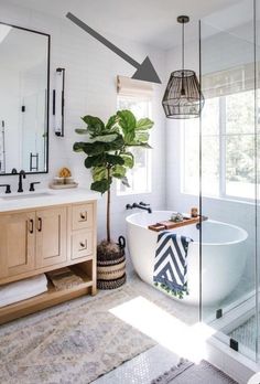 a bathroom with a bathtub, sink and mirror next to a potted plant